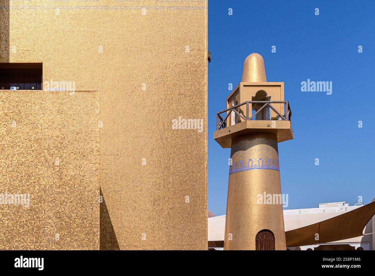 Doha, Qatar - 4 gennaio 2025: Un minareto dorato si erge alto contro il cielo azzurro del Katara Cultural Village, esemplificando la fusione di trad Foto Stock