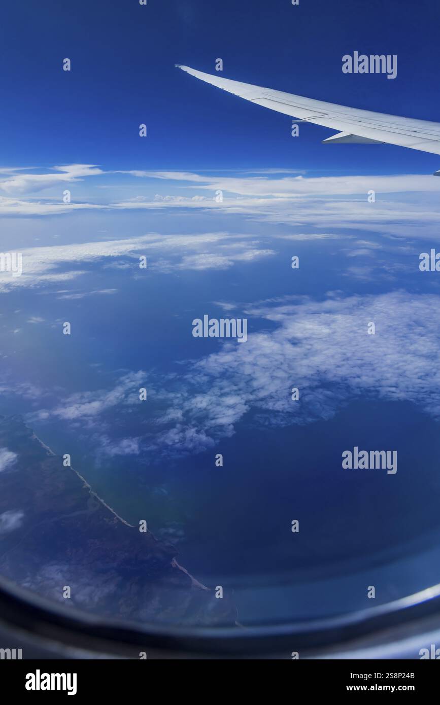 Vista dalla finestra dell'aeromobile durante un volo sull'India con la compagnia aerea Etihad. Cielo blu e strutture nuvolose sul mare, ala di un Boeing 787 Air Foto Stock