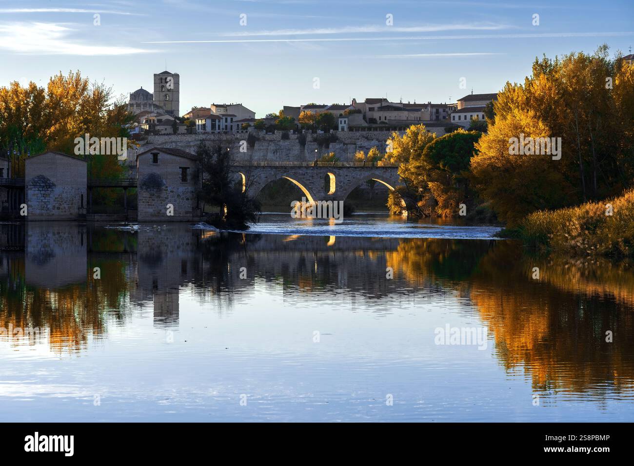 Vista della città di Zamora, dei mulini ad acqua e della cattedrale romanica in autunno al tramonto che si riflette nel fiume Duero Rin Foto Stock