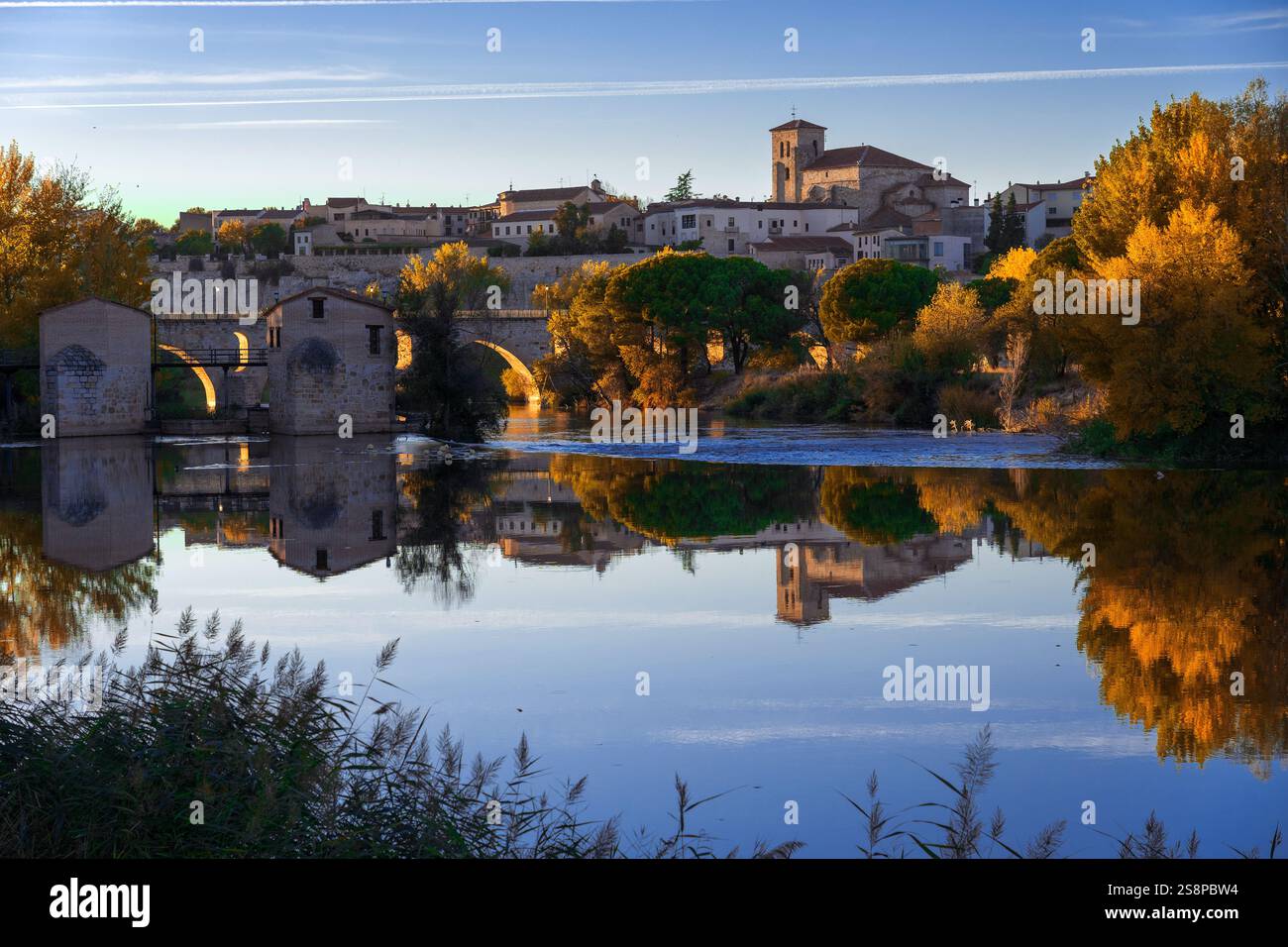 Vista della città di Zamora, dei mulini ad acqua e della chiesa di San Pedro sullo sfondo in autunno al tramonto riflesso nel fiume Foto Stock