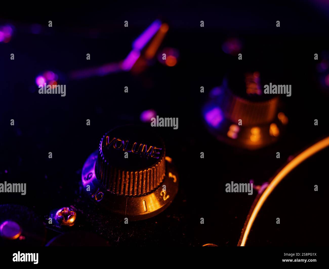 Chitarra elettrica da vicino. Manopola del volume. Dettagli dello strumento musicale. Luci a contrasto a colori per concerti. Chitarra a sei corde durante l'esibizione. Colori brillanti Foto Stock