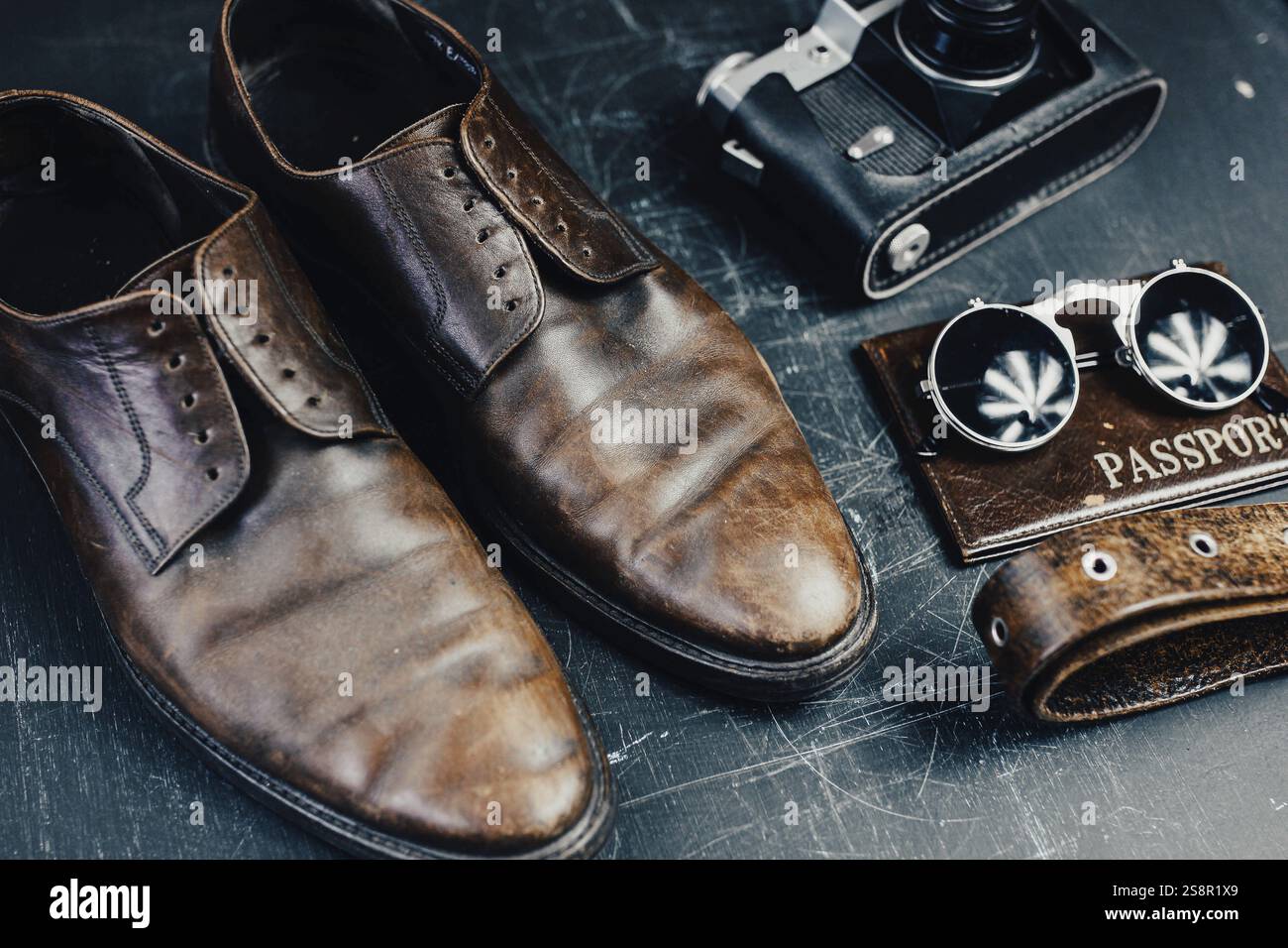 Scarpe marroni e accessori da viaggio vintage disposti su sfondo scuro Foto Stock