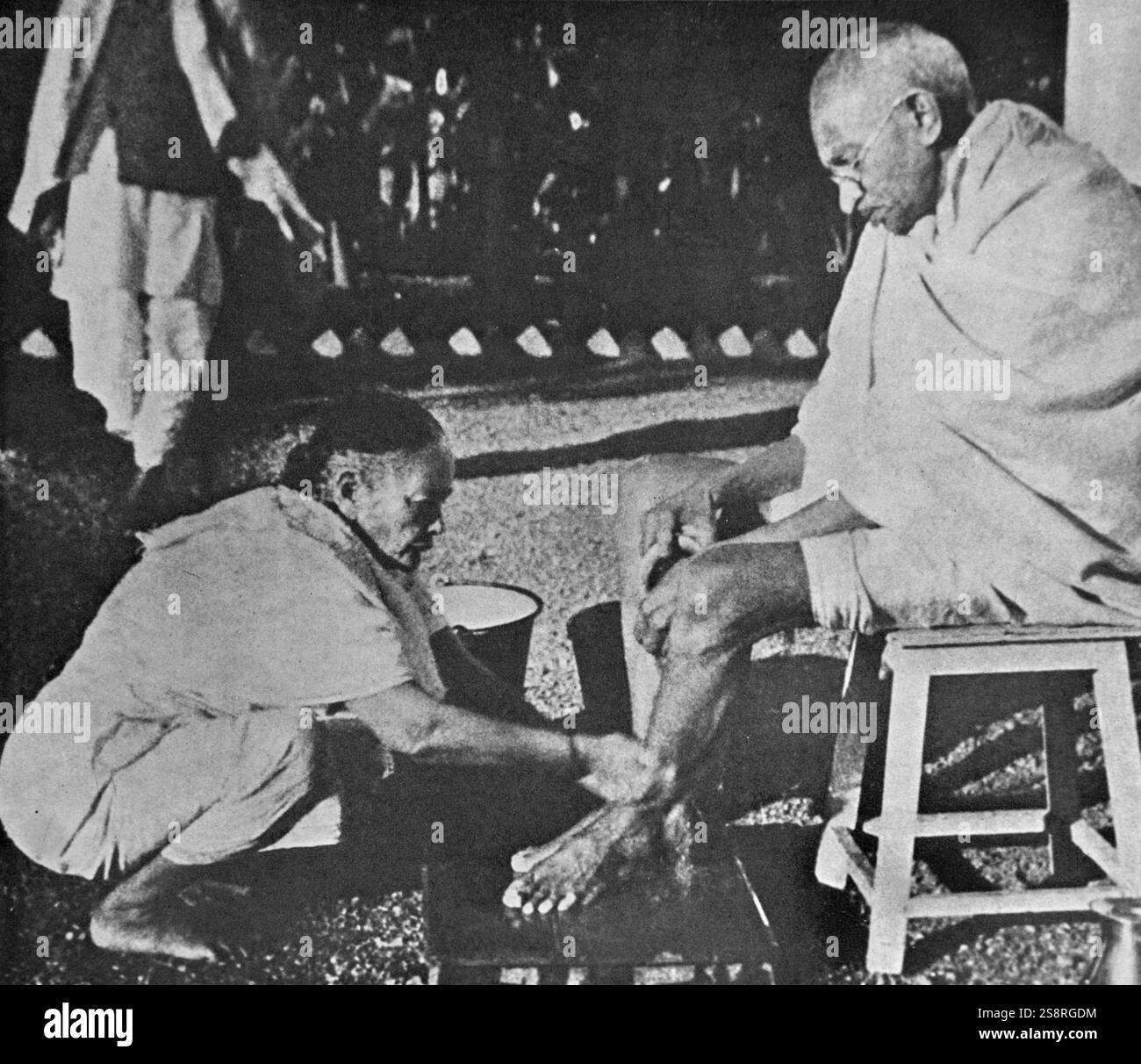 Il Mahatma Gandhi avente il suo lavaggio dei piedi, da sua moglie Kasturba, a Sevagram un villaggio nello stato di Maharashtra, India. Sevagram era il luogo di Mohandas Gandhi Ashram e la sua residenza da 1936 fino alla sua morte nel 1948 Foto Stock