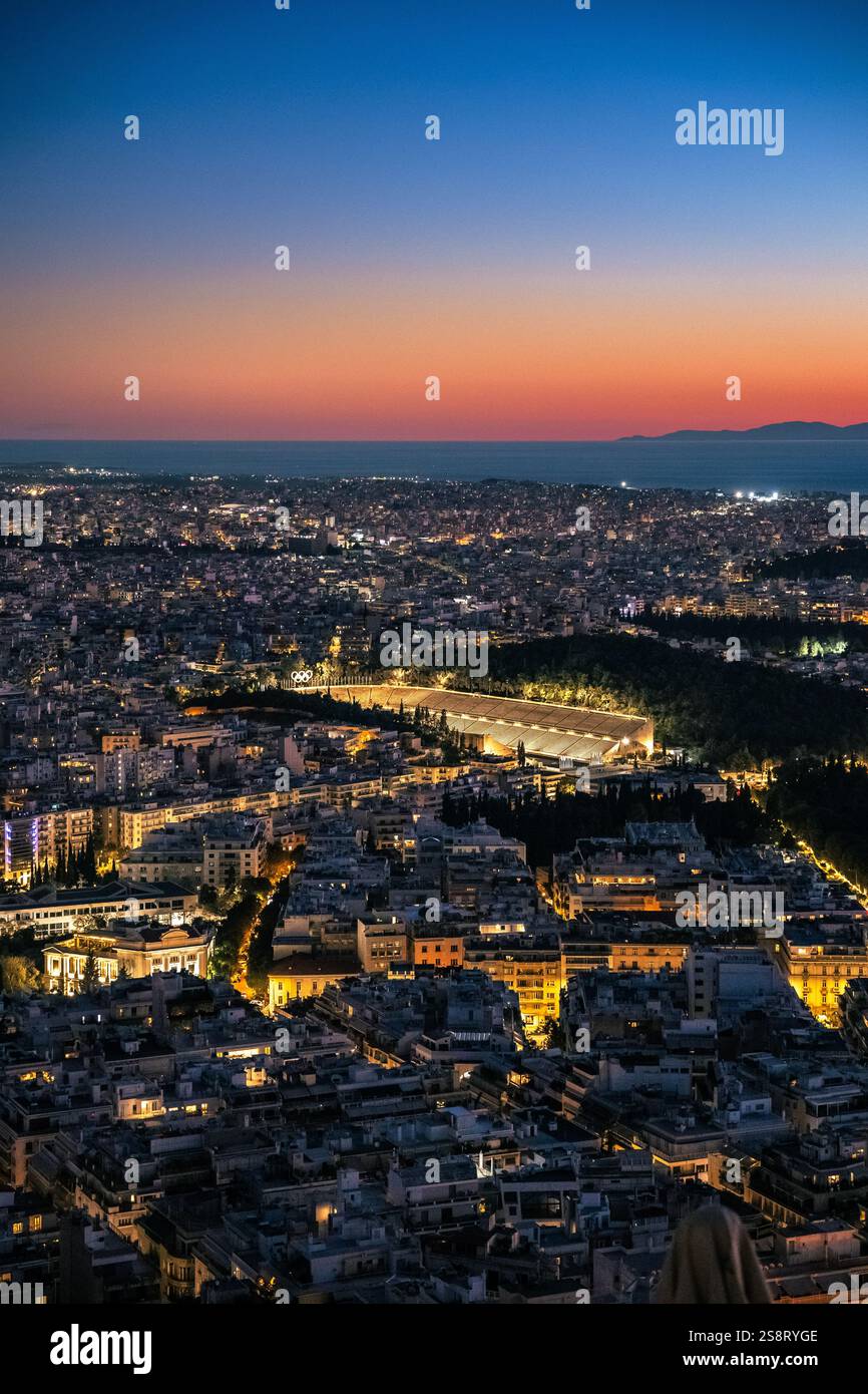 Vista verticale sullo skyline illuminato di Atene, Grecia, con lo stadio Panatenaico di Atene, Grecia al tramonto. Antico Stadio Olimpico Foto Stock