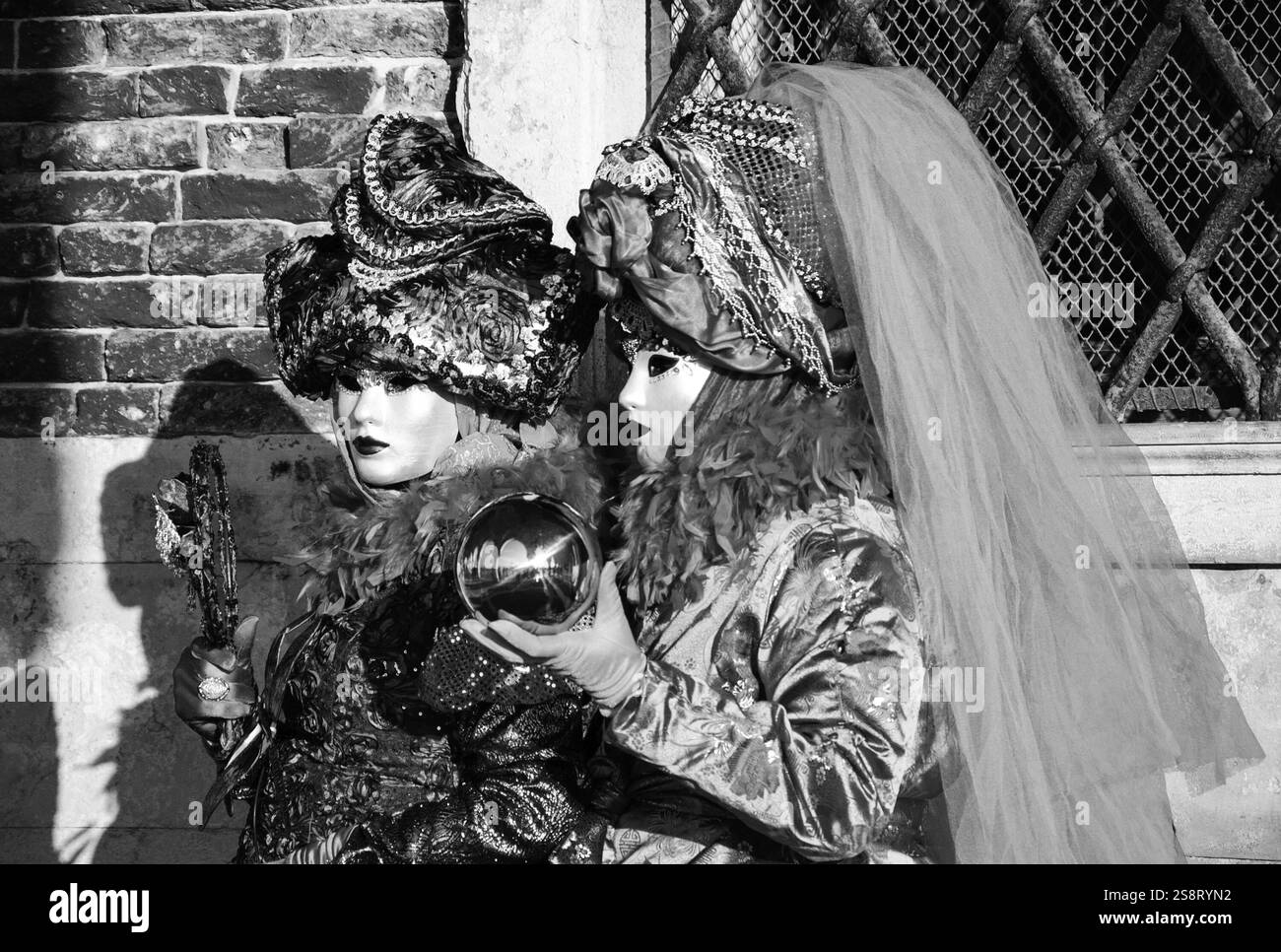 VENEZIA, ITALIA - 16 FEBBRAIO 2015: Due maschere (con sfera in mano con riflesso del Palazzo Ducale) in Piazza San Marco durante il tradizionale Carnevale. Carniva Foto Stock