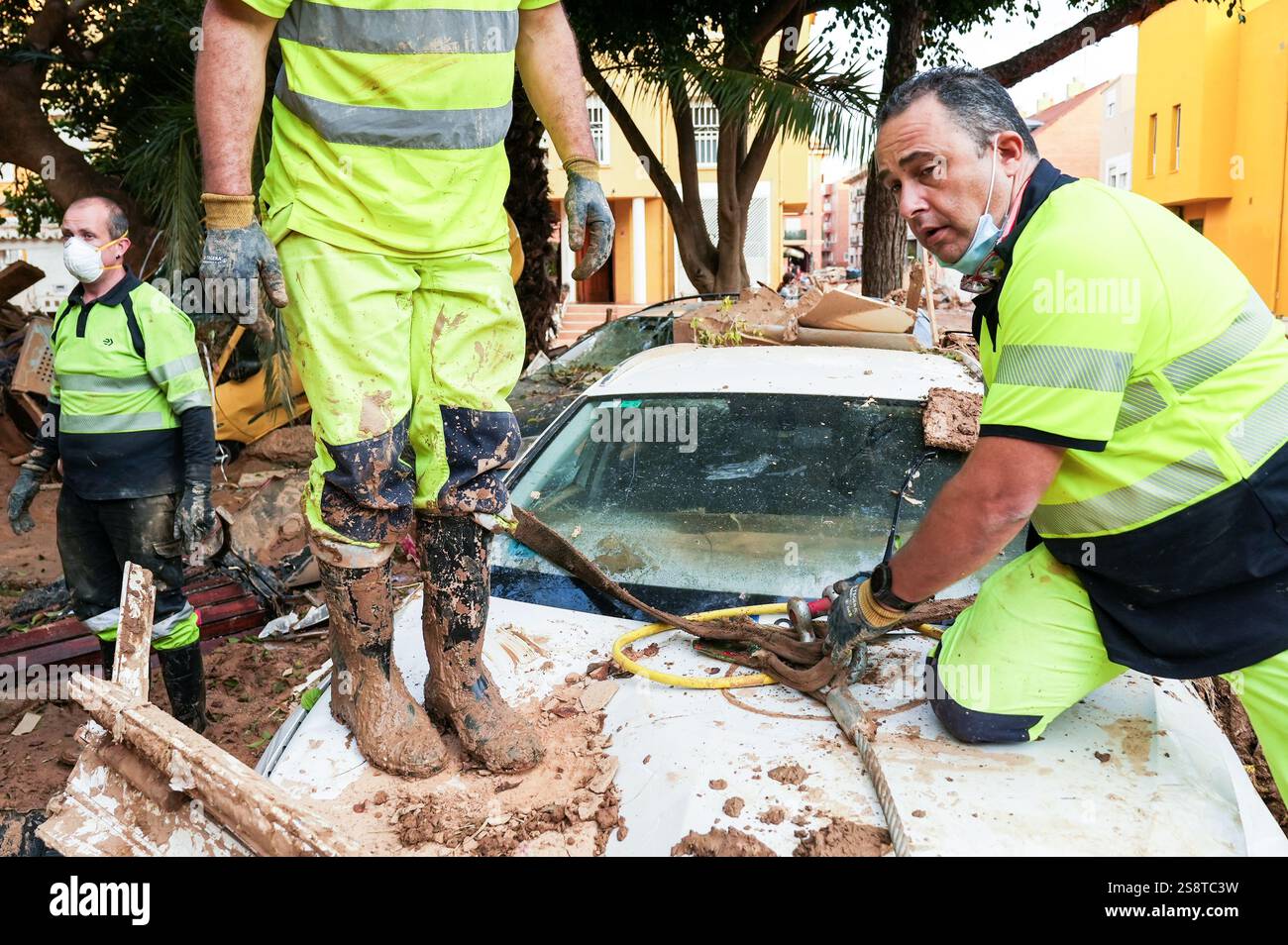 Lavoratori di EMT Madrid durante le operazioni di pulizia di auto schiacciate dopo l'inondazione DANA. Lavoratori che rimuovono le auto bloccate nel fango. Alfafar, Spagna. Foto Stock