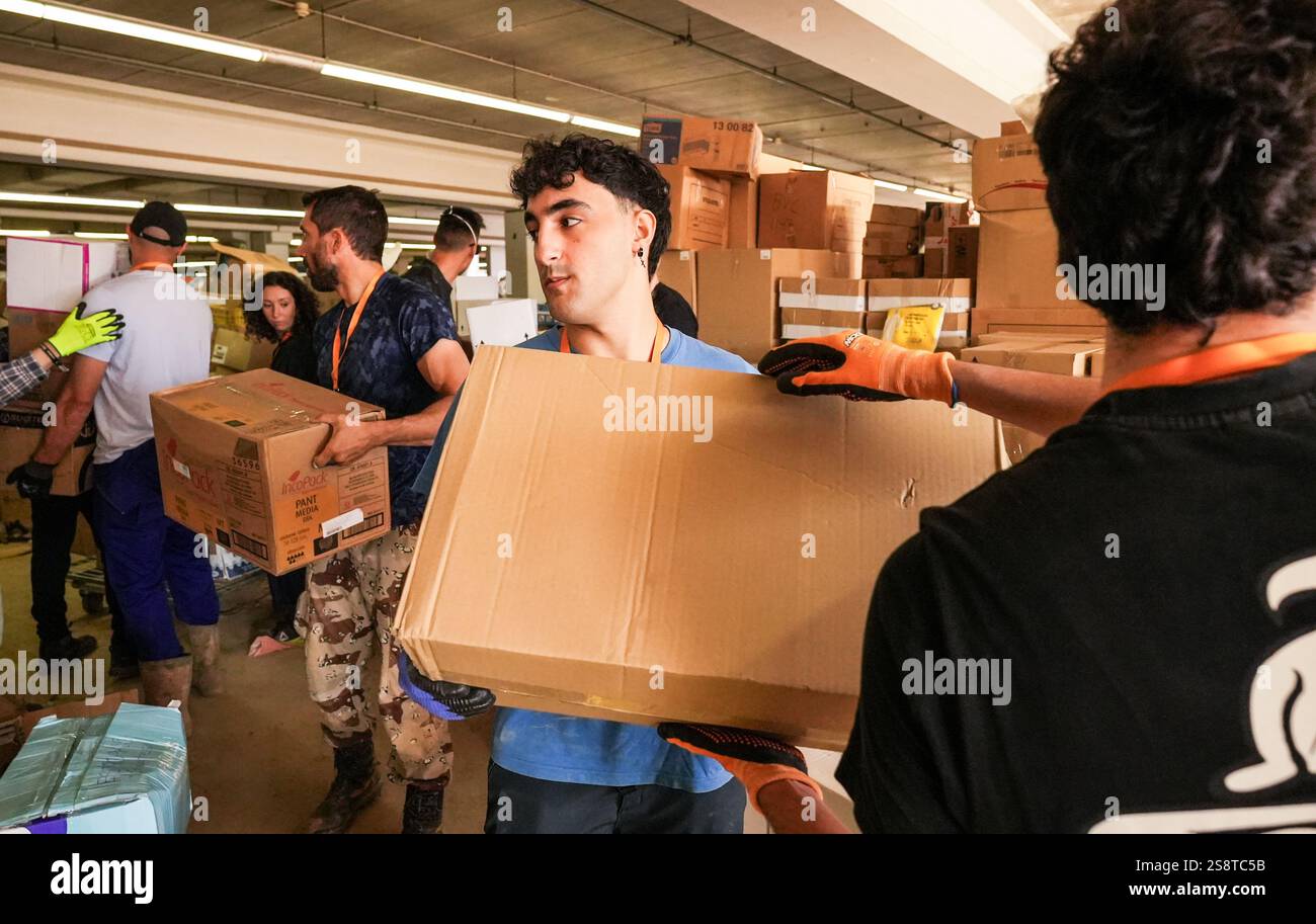 Lavoratori che passano scatole di cartone nel magazzino di emergenza di IKEA Alfafar per fornire aiuto umanitario e sostegno alle aree colpite da DANA. Foto Stock