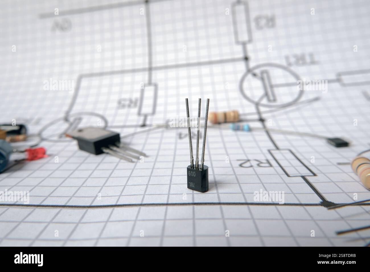 Componenti elettronici in piedi sullo schema elettrico con transistor e resistore. Controllato sul transistor. Foto Stock