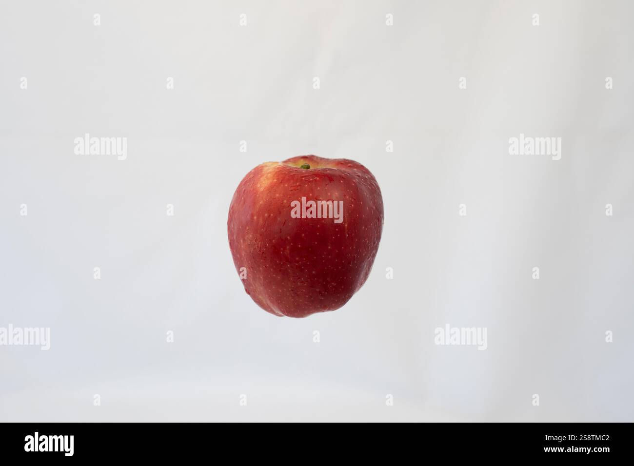Mela rossa che galleggia a mezz'aria su sfondo bianco isolato: Concetto minimalista per mangiare sano, freschezza e stile fotografico Clean Food Foto Stock
