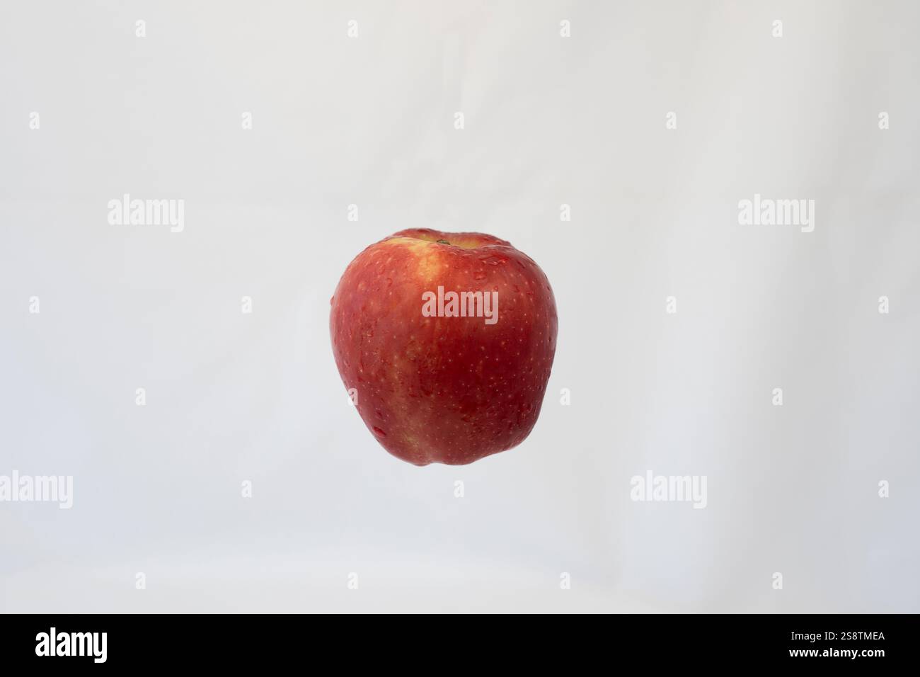 Mela rossa che galleggia a mezz'aria su sfondo bianco isolato: Concetto minimalista per mangiare sano, freschezza e stile fotografico Clean Food Foto Stock