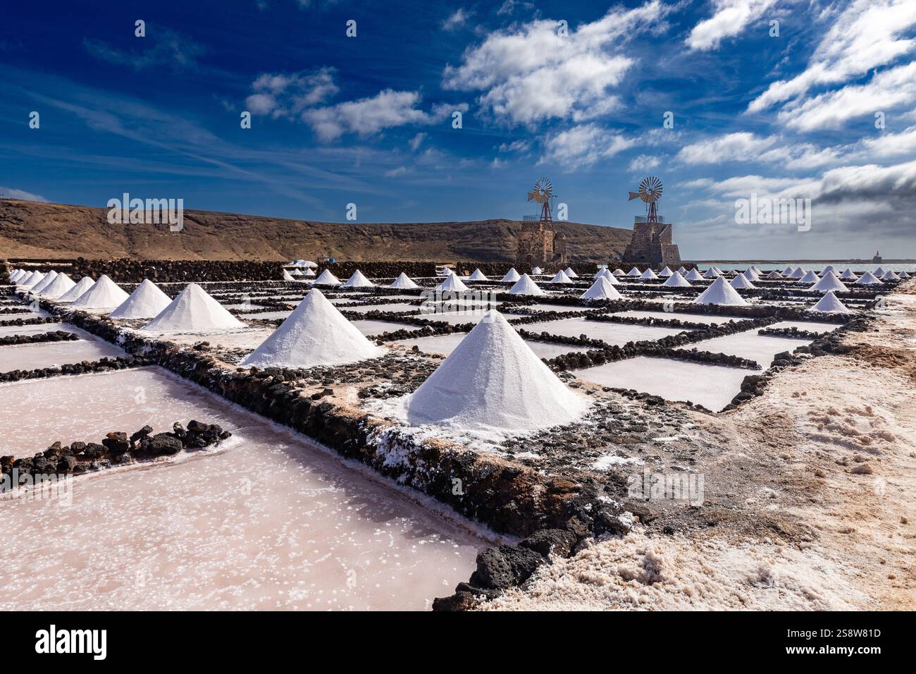 Pile di sale raccolto formano forme geometriche impressionanti attraverso le Salinas del Janubio a Lanzarote. I tumuli riflettono la luce sotto un cielo nuvoloso, vetrina Foto Stock