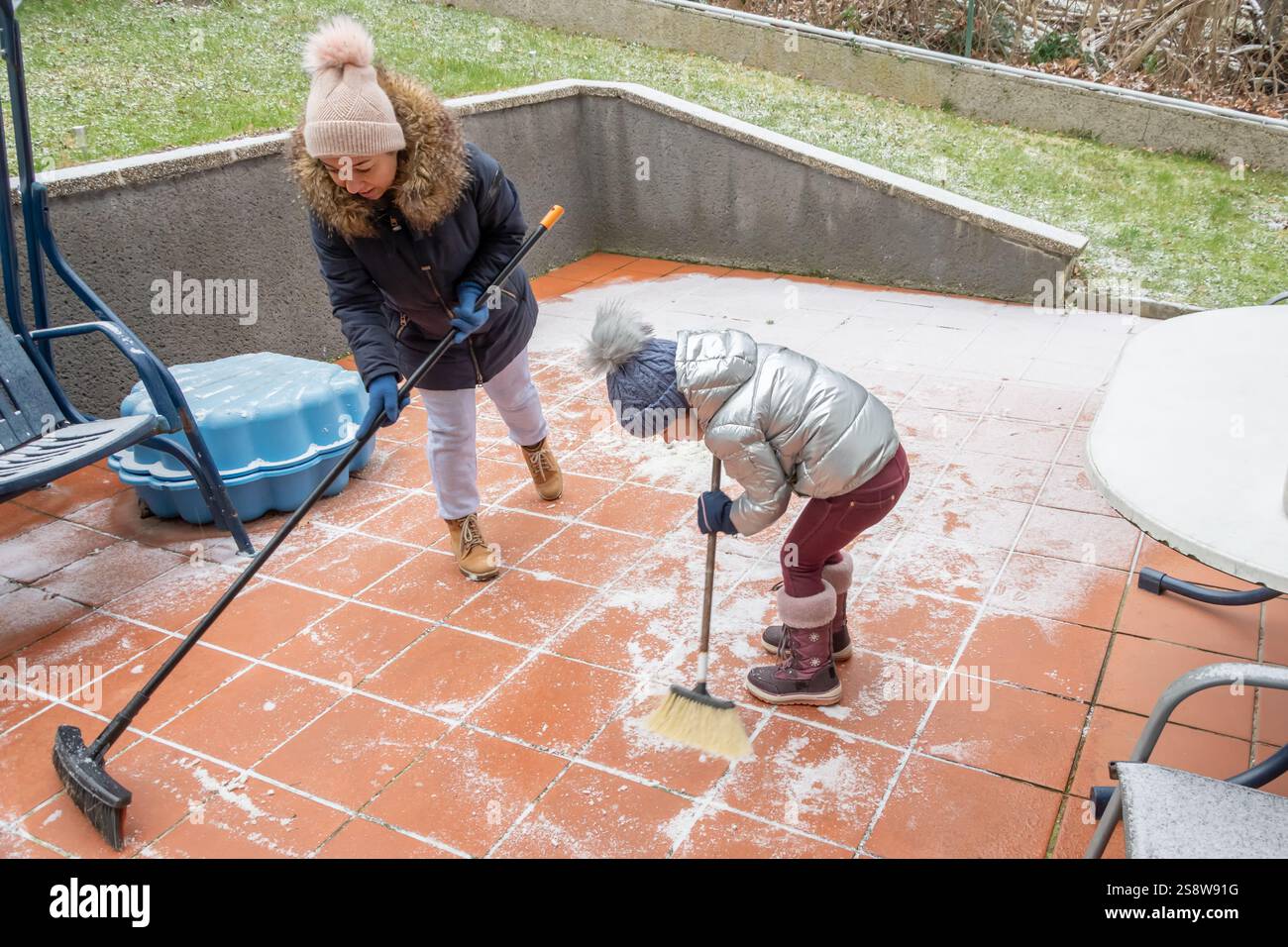 Un bambino in abiti caldi aiuta la mamma a pulire la neve Foto Stock