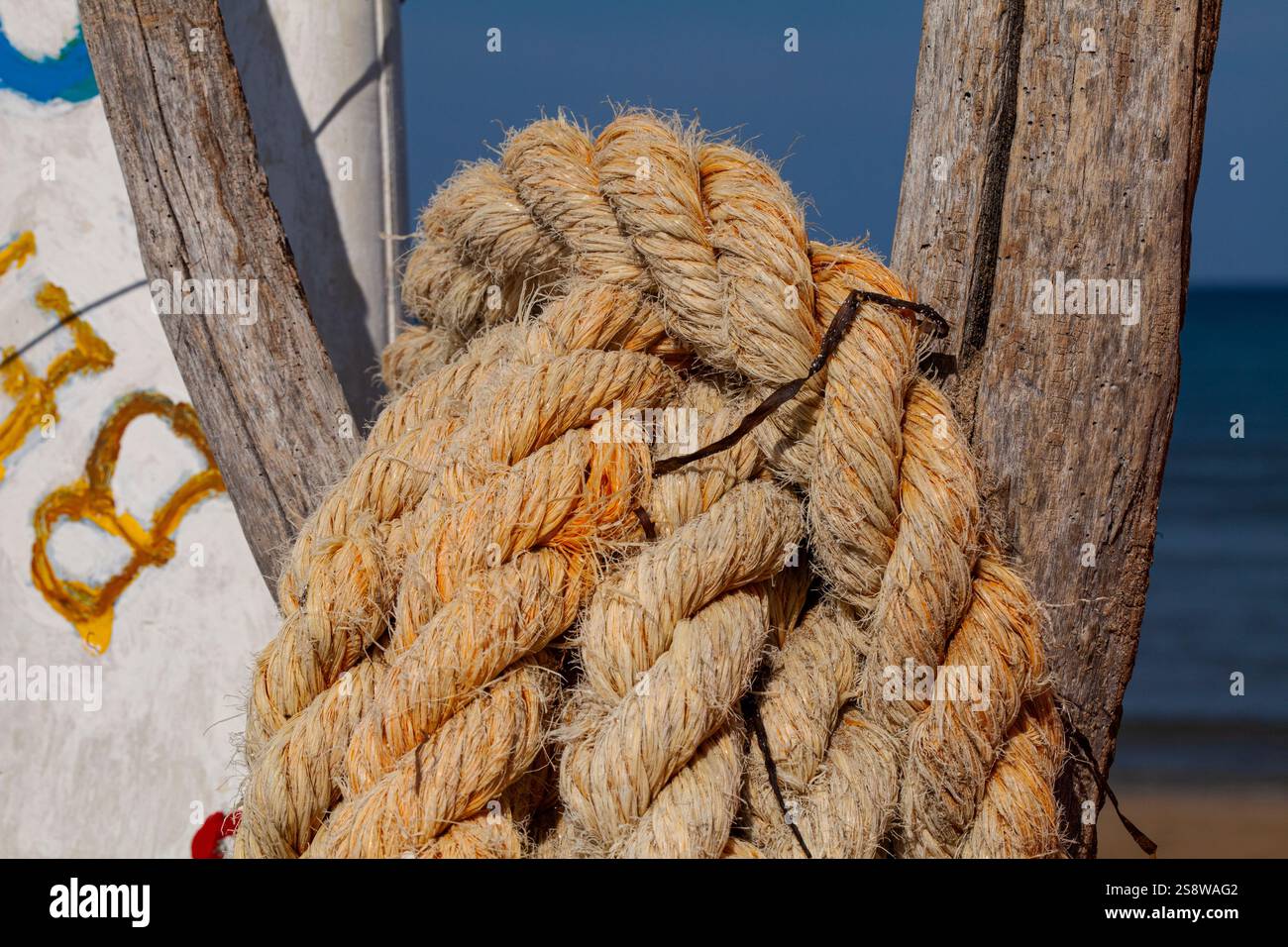 Un'atmosfera marinara su una delle coste dell'Adriatico. Una corda nautica intemprata, sbiadita dal sole, assicurata su una tavola da surf vintage. Foto Stock