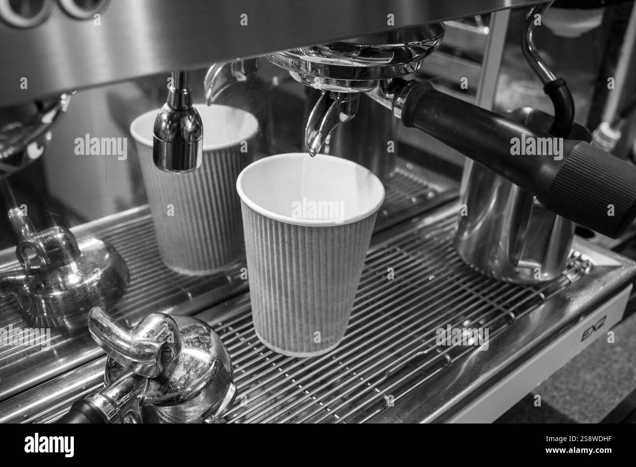 Una macchina per il caffè con una tazza di caffè. La macchina per il caffè è in bianco e nero. Foto Stock