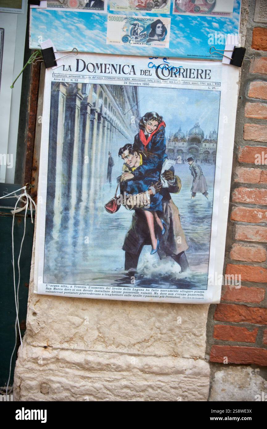 La vecchia copertina della rivista italiana "la domenica del Corriere" esposta su un muro veneziano, che mostra la scena delle inondazioni in Piazza San Marco con fascino nostalgico Foto Stock