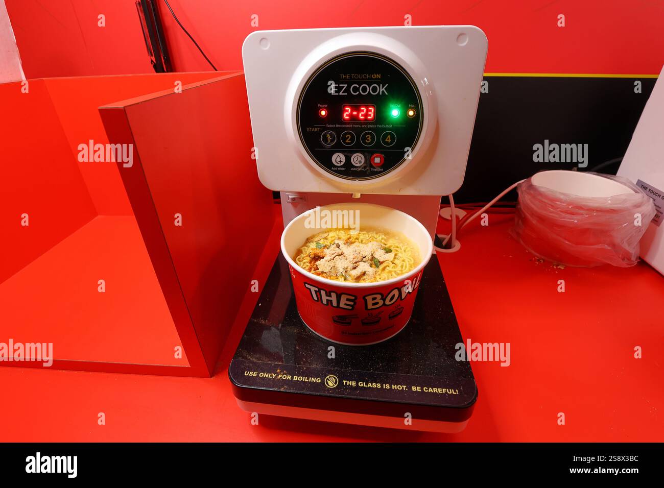 Una cucina di ramen istantaneo Touch On Ez Cook self-service con un pacchetto di Nongshim Ramyun in una ciotola di carta riscaldabile a induzione cucinata a induzione Foto Stock