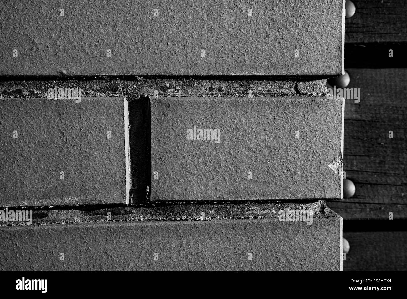 Primo piano dettagliato di mattoni grigi testurizzati con linee di Malta visibili e sfondo in legno Foto Stock