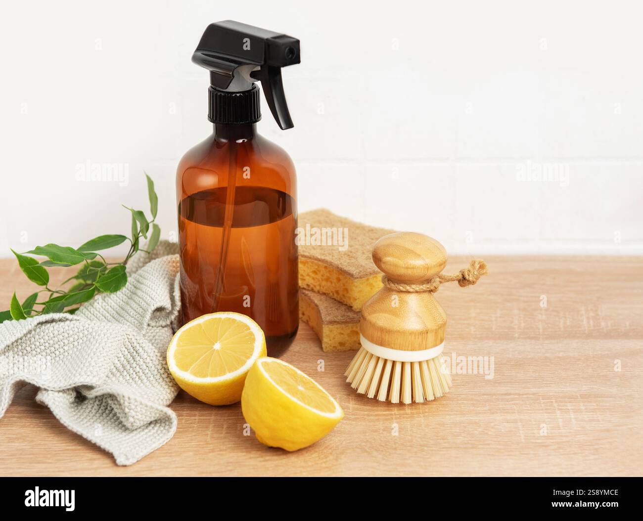 Prodotti per la pulizia naturali, spazzola per piatti, flacone di limone e spray su un tavolo in legno per uno stile di vita sostenibile Foto Stock