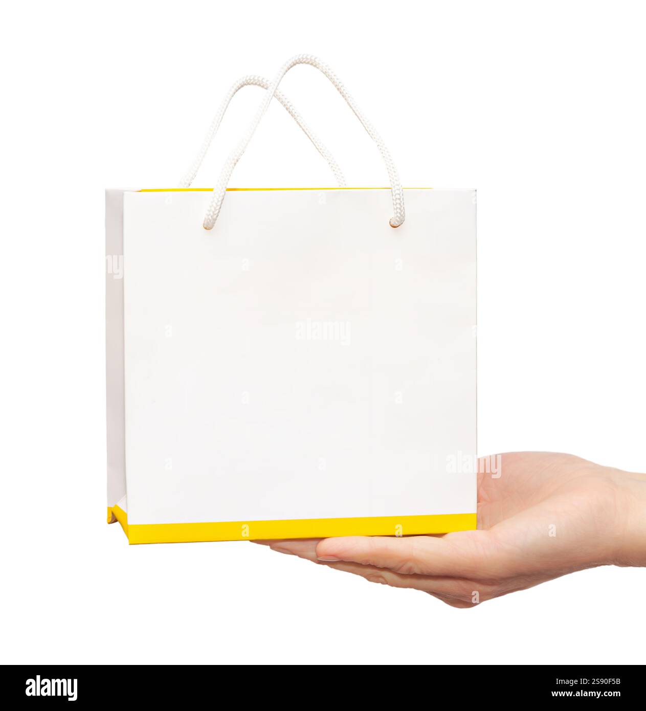 Una mano espone una piccola confezione regalo vuota, con parte superiore bianca e allegra base gialla, perfetta per il branding creativo o la donazione di regali. Foto Stock