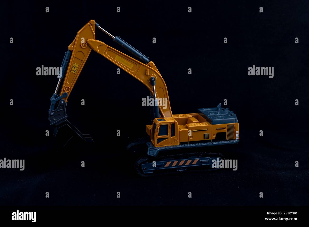 Escavatore giocattolo o scavatore su sfondo nero. Concetto di veicolo per costruzioni pesanti. Foto Stock