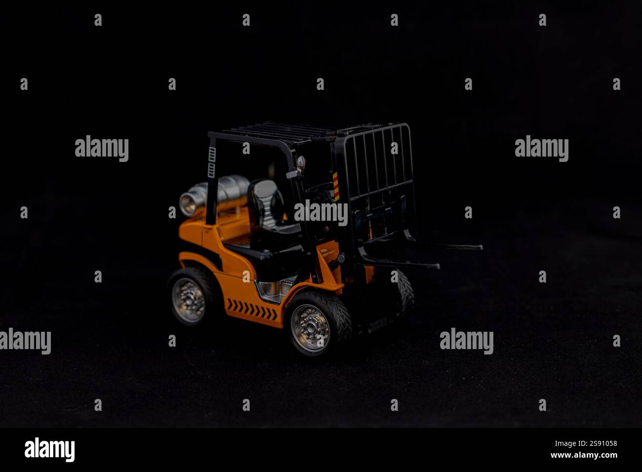 Carrello elevatore a forche in miniatura che trasporta pallet vuoto su sfondo nero Foto Stock