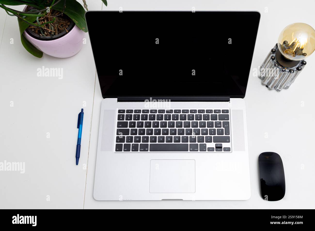 Spazio di lavoro minimalista con laptop, penna, mouse e impianto interno Foto Stock