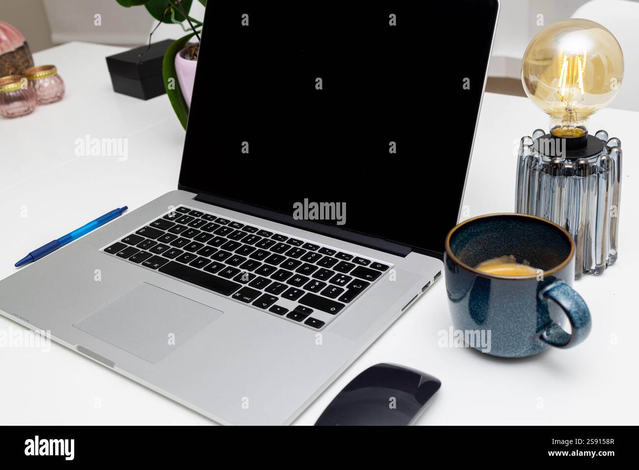 Elegante spazio di lavoro con laptop, tazza da caffè, penna e lampada Foto Stock
