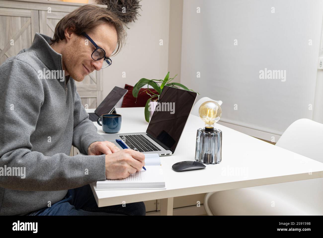 un imprenditore sta scrivendo nel suo libro e pianificando la sua giornata Foto Stock