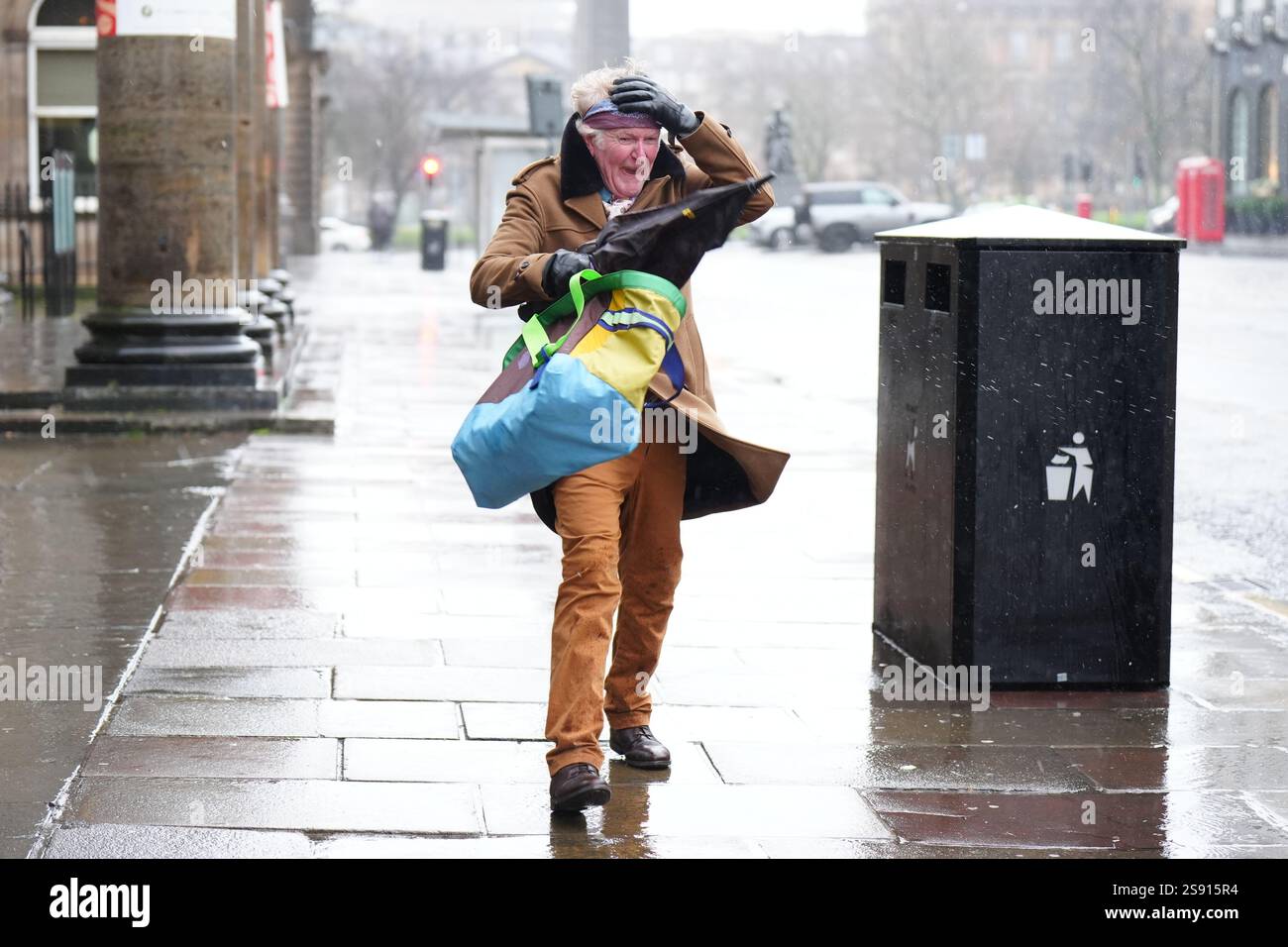 Un membro delle battaglie pubbliche contro il vento durante la tempesta Eowyn in George Street, Edimburgo. Le scuole sono state chiuse e la gente ha avvertito di non viaggiare venerdì, poiché i venti a 100 km/h rappresentano un pericolo per la vita in alcune parti del Regno Unito mentre la tempesta Eowyn colpisce il paese. Data foto: Venerdì 24 gennaio 2025. Foto Stock