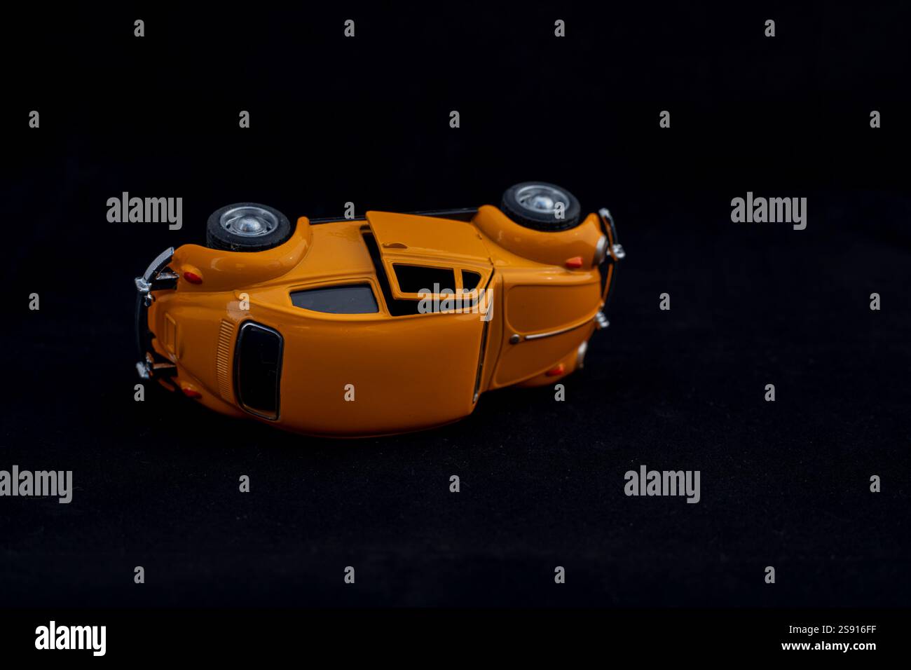 Toy Car d'epoca capovolta su sfondo nero. Concetto di incidente stradale. Foto Stock