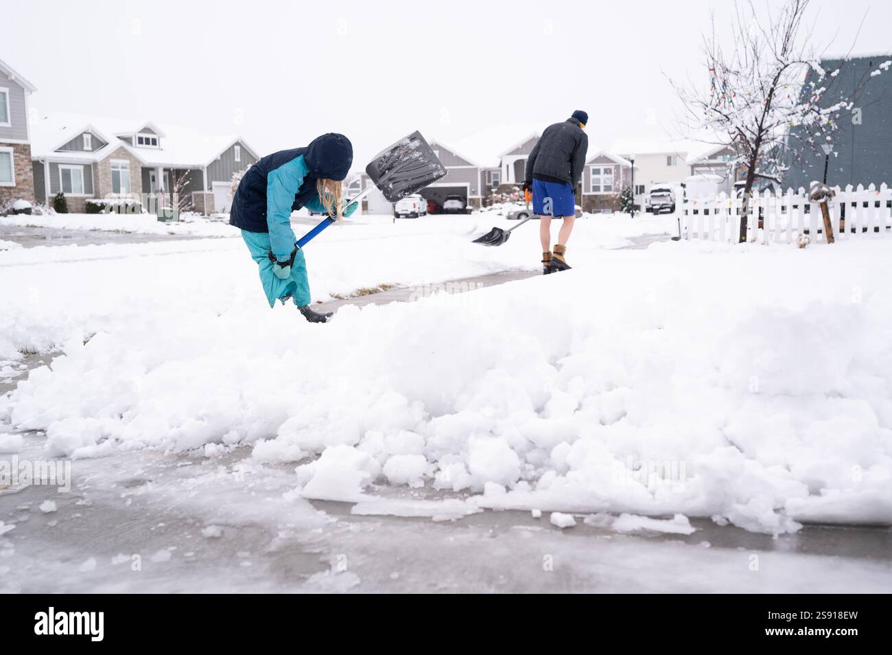 Padre e figlia spalancano la neve nel quartiere periferico Foto Stock