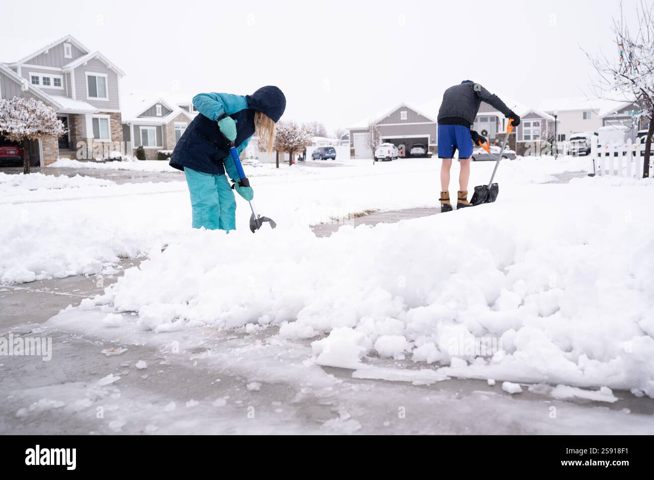 Padre e figlia spalancano la neve nel quartiere Foto Stock