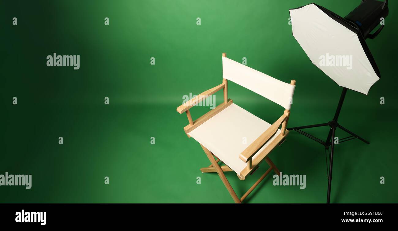 Studio fotografico con sfondo verde e sgabello in legno con illuminazione professionale. Interno dello studio fotografico con illuminazione professionale Foto Stock