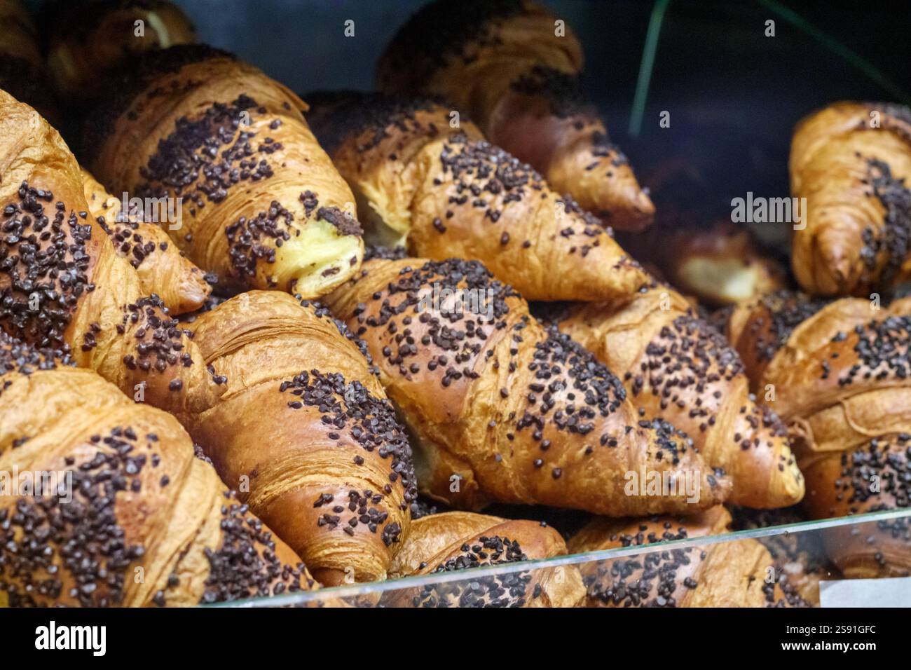 Diversi cupcake freschi e dall'aspetto delizioso cosparsi di gocce di cioccolato e collocati in una vetrina di vetro. Foto Stock