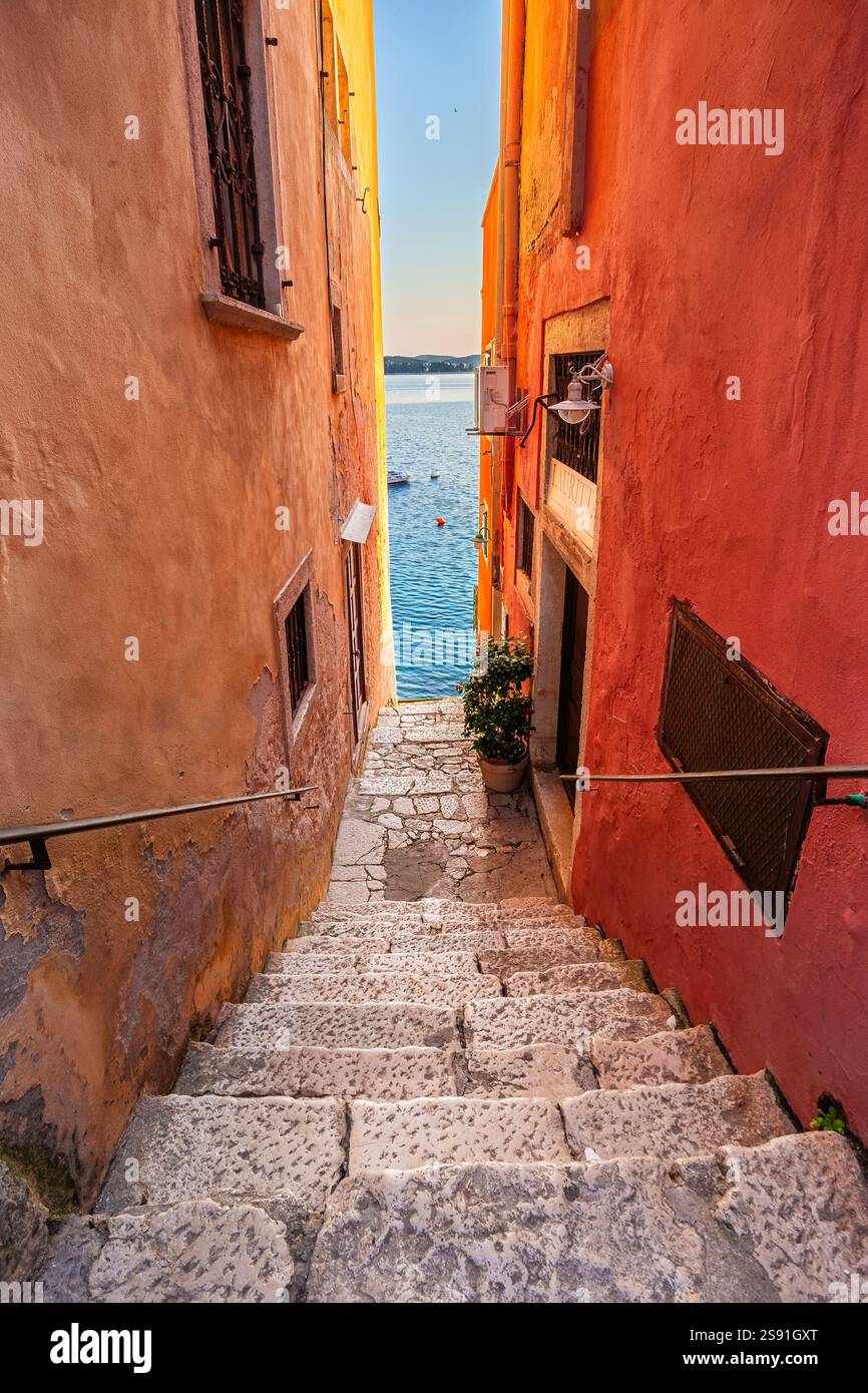 Rovigno, Croazia - tradizionale vicolo acciottolato croato che conduce al mare con cielo azzurro e acqua blu del mare Adriatico su un caldo summ soleggiato Foto Stock