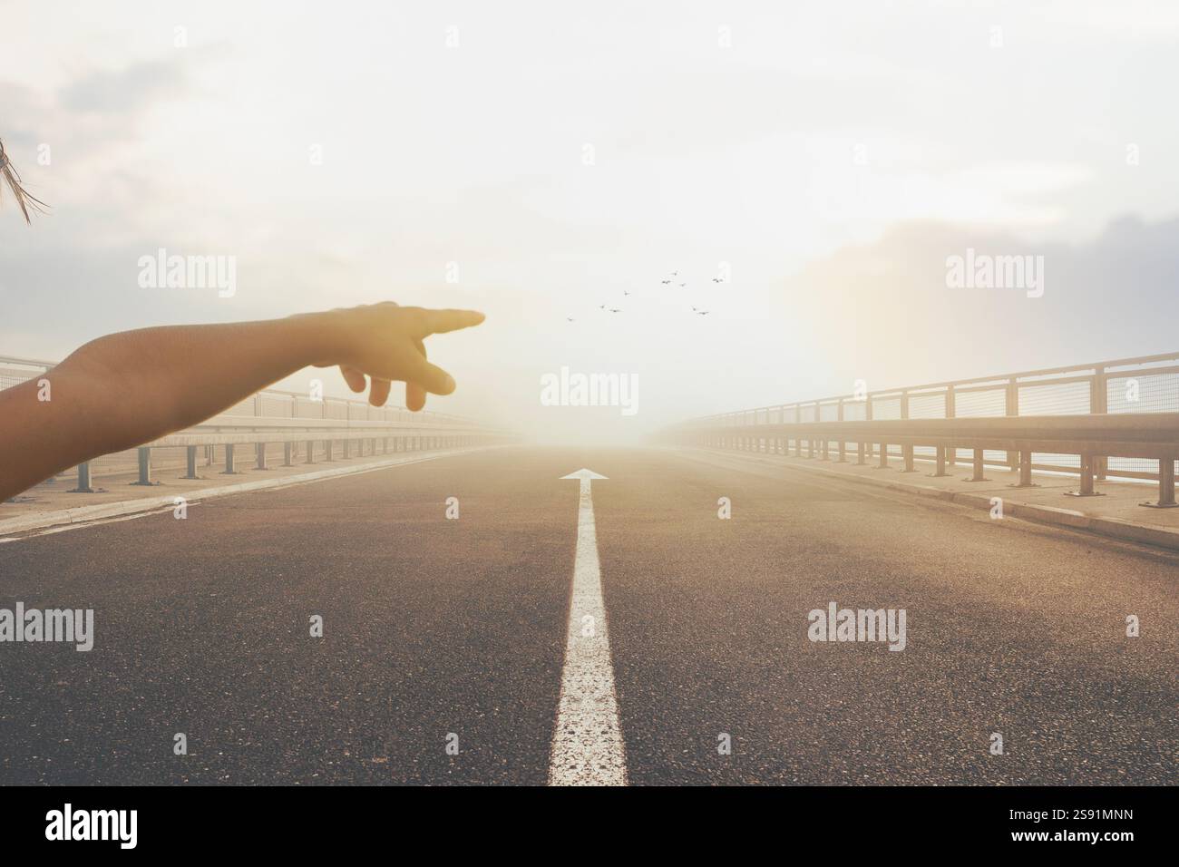 Persona che punta verso il tramonto sulla strada deserta con l'ambiente Center Arrow Foto Stock