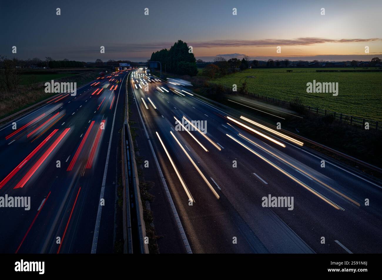 Sentieri leggeri formati dal traffico che viaggia verso e lontano dalla telecamera, sull'autostrada M6, al crepuscolo di una sera d'inverno. Foto Stock