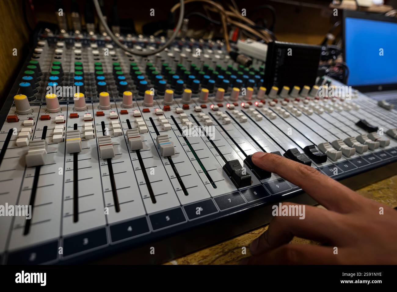 La mano maschile regola la scala in base alla workstation Digital Sound accanto al router e al desktop. Una consolle di miscelazione per la configurazione e la registrazione close-u Foto Stock