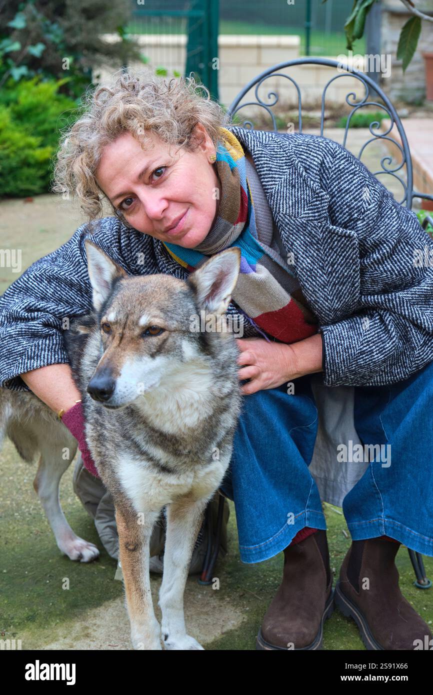 Donna che abbraccia il cane del lupo cecoslovacco in giardino Foto Stock