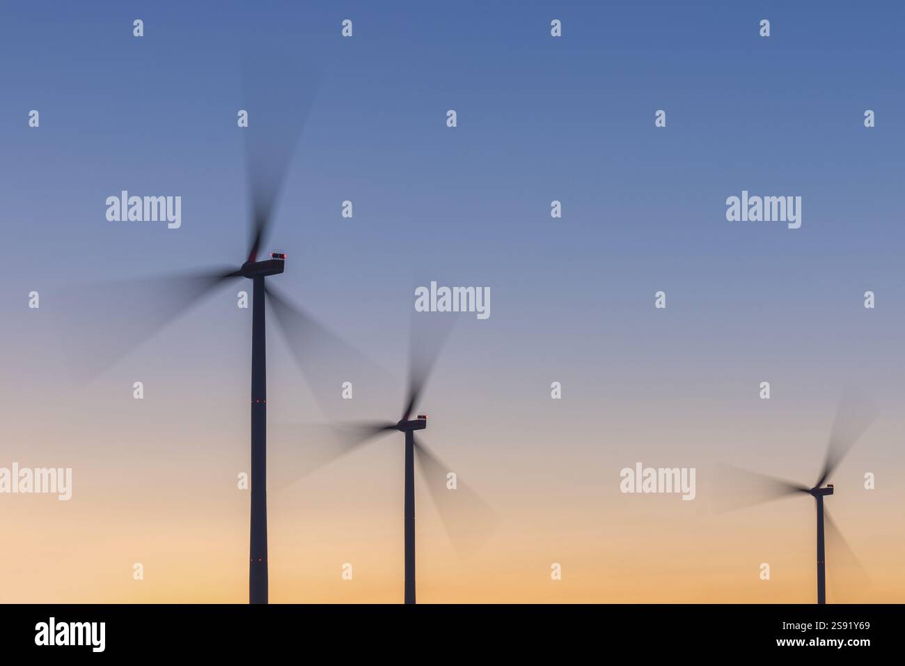 Tre turbine eoliche di fronte a un cielo colorato al tramonto, che si muovono rapidamente nel vento, Rems Valley, Baden-Wuerttemberg, Germania, Europa Foto Stock