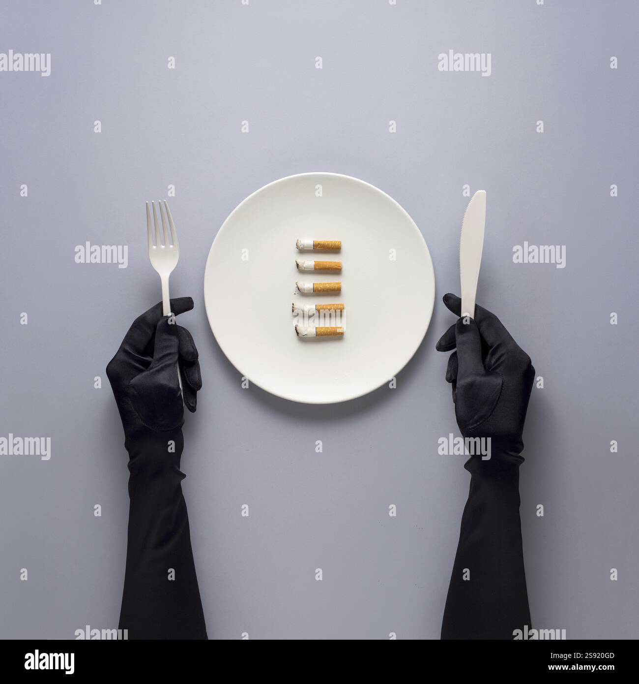 Foto creativa di oggetti da cucina con piatto dipinto a mano e sigarette su sfondo grigio Foto Stock