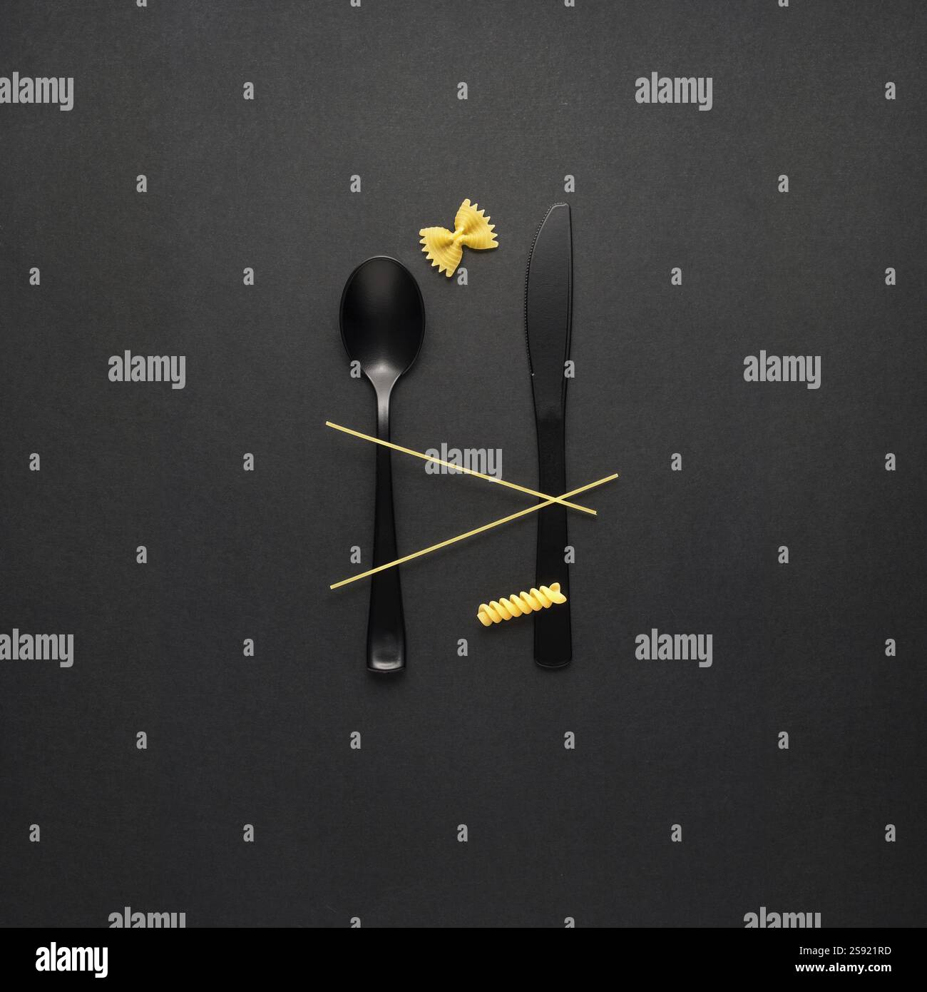 Foto creative di STILL Life con forchetta e cucchiaio con pasta cruda su sfondo nero Foto Stock