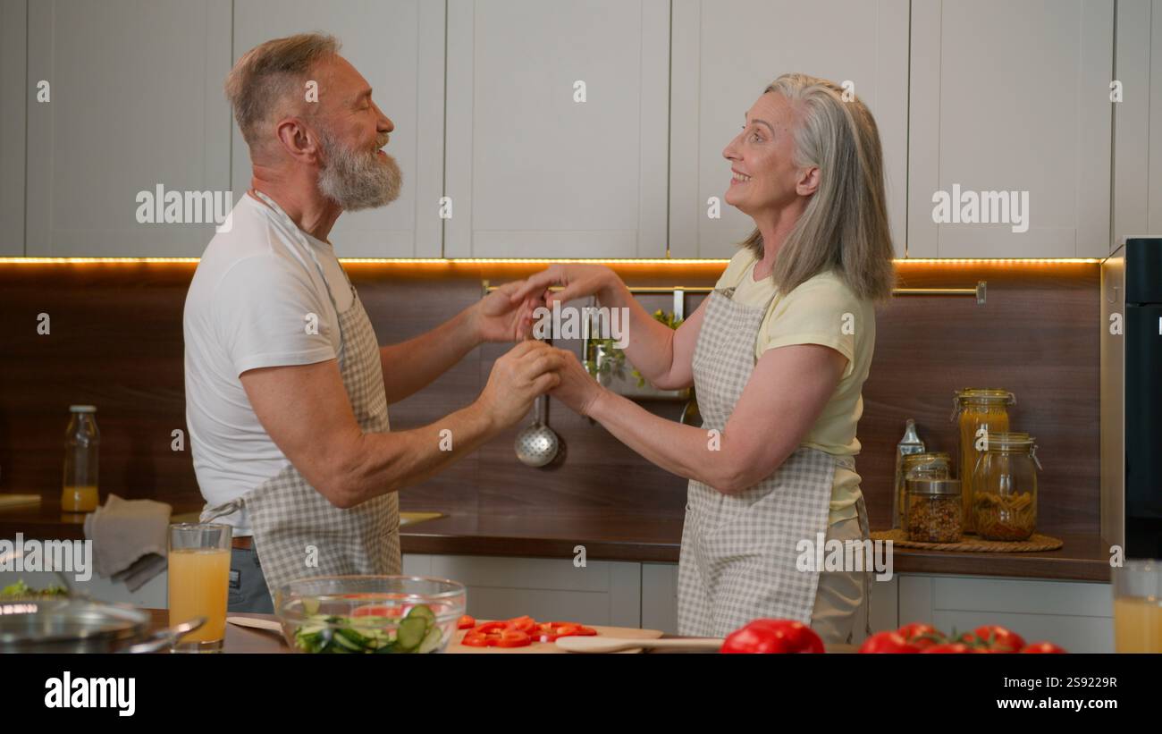 Caucasico coppia d'amore felice famiglia in pensione vecchio uomo maturo e donna che cucinano in cucina casalinga romantico danza nonna nonno che festeggia Foto Stock