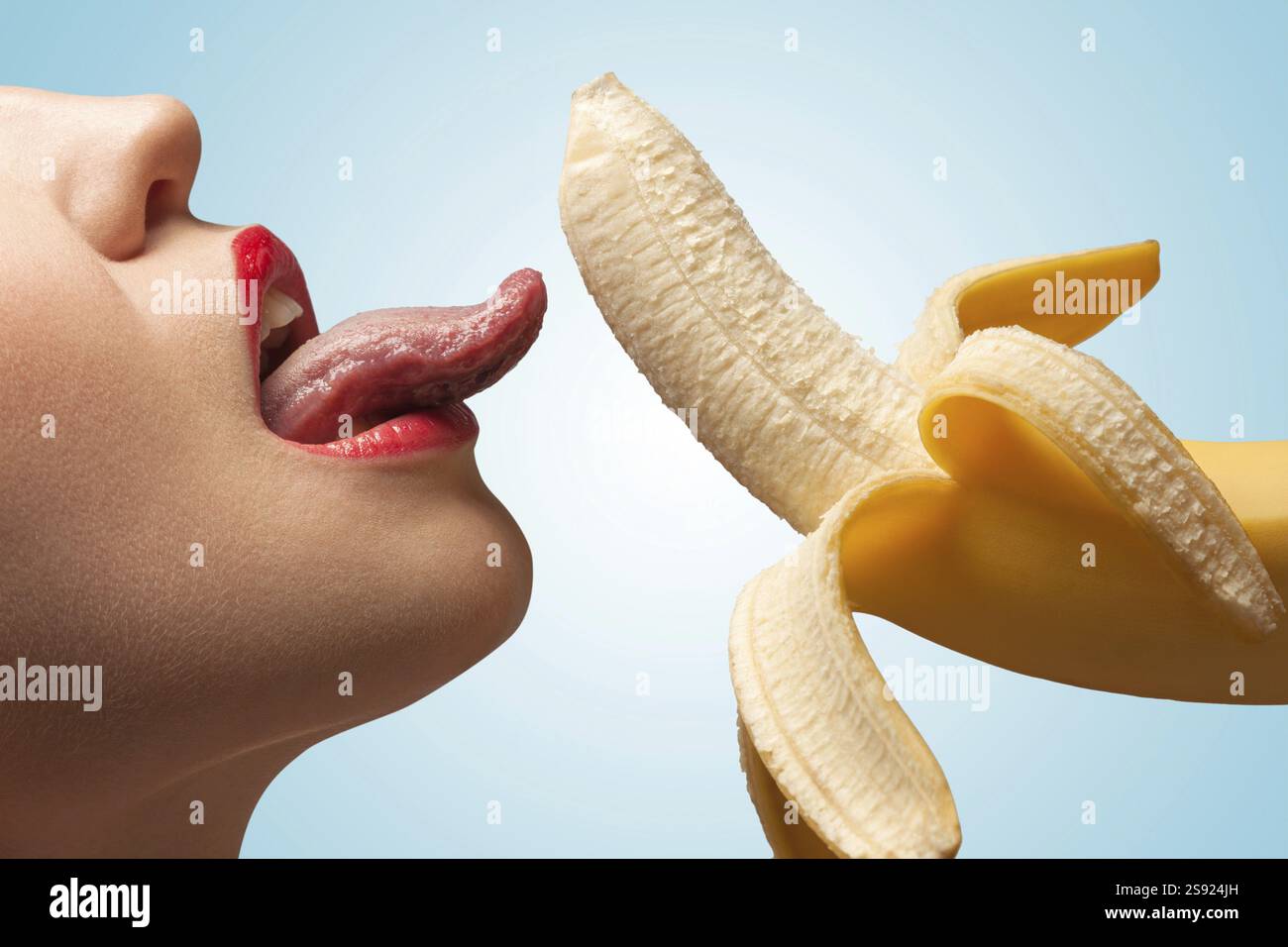 Il volto di una ragazza bollente che lecca una banana gialla mezza pelata Foto Stock