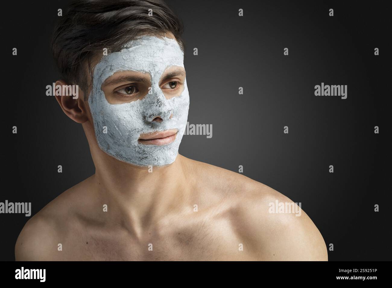 Ritratto di un giovane uomo bello e rilassato con una maschera facciale in argilla, cura della pelle per il viso e il corpo Foto Stock