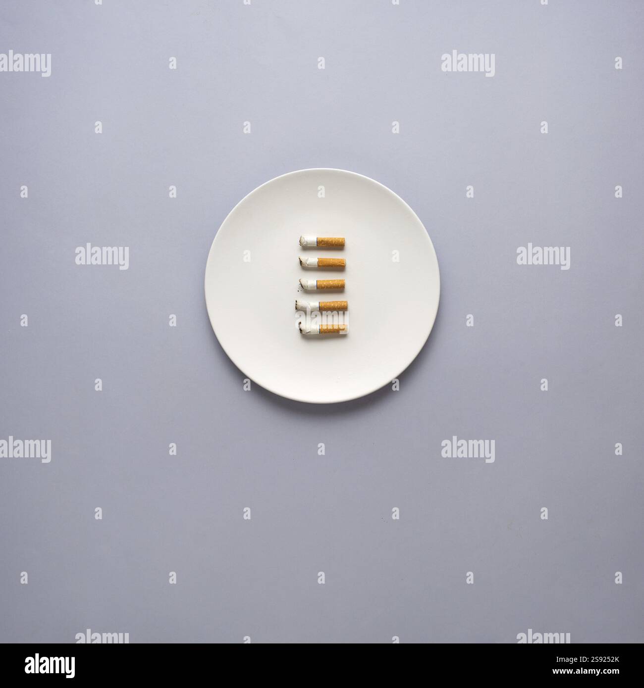 Foto creativa di oggetti da cucina con piatto dipinto a mano e sigarette su sfondo grigio Foto Stock