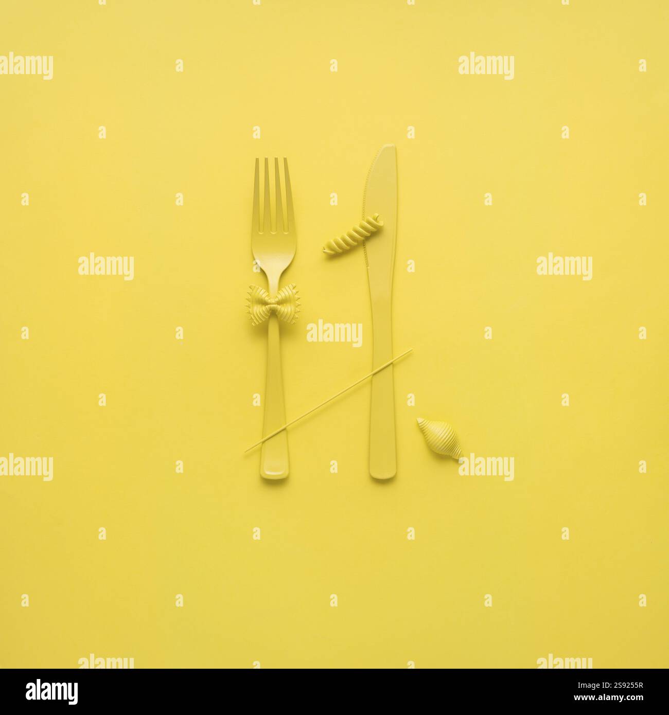 Foto creative di STILL Life con forchetta e cucchiaio con pasta cruda su sfondo giallo Foto Stock