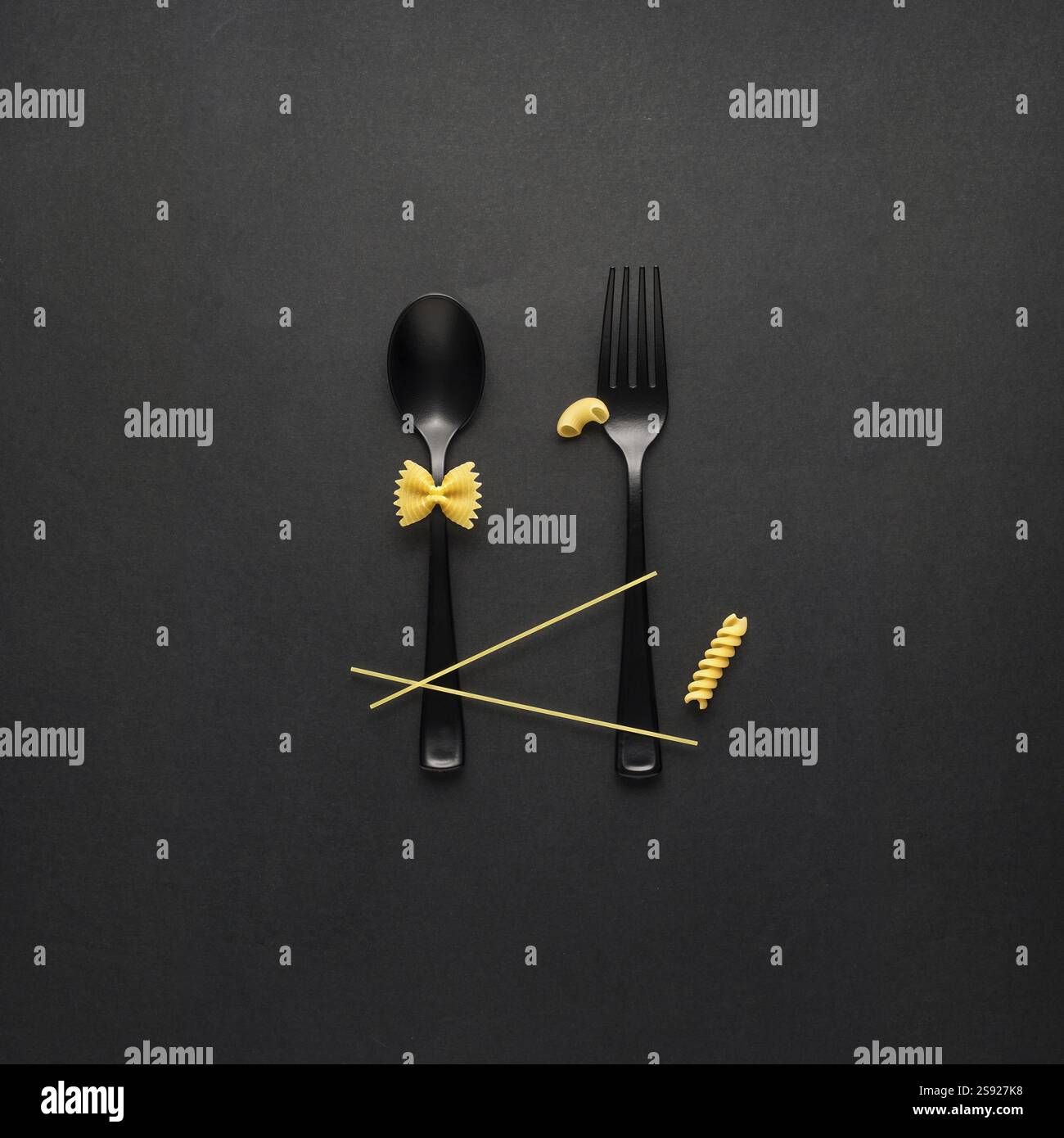 Foto creative di STILL Life con forchetta e cucchiaio con pasta cruda su sfondo nero Foto Stock