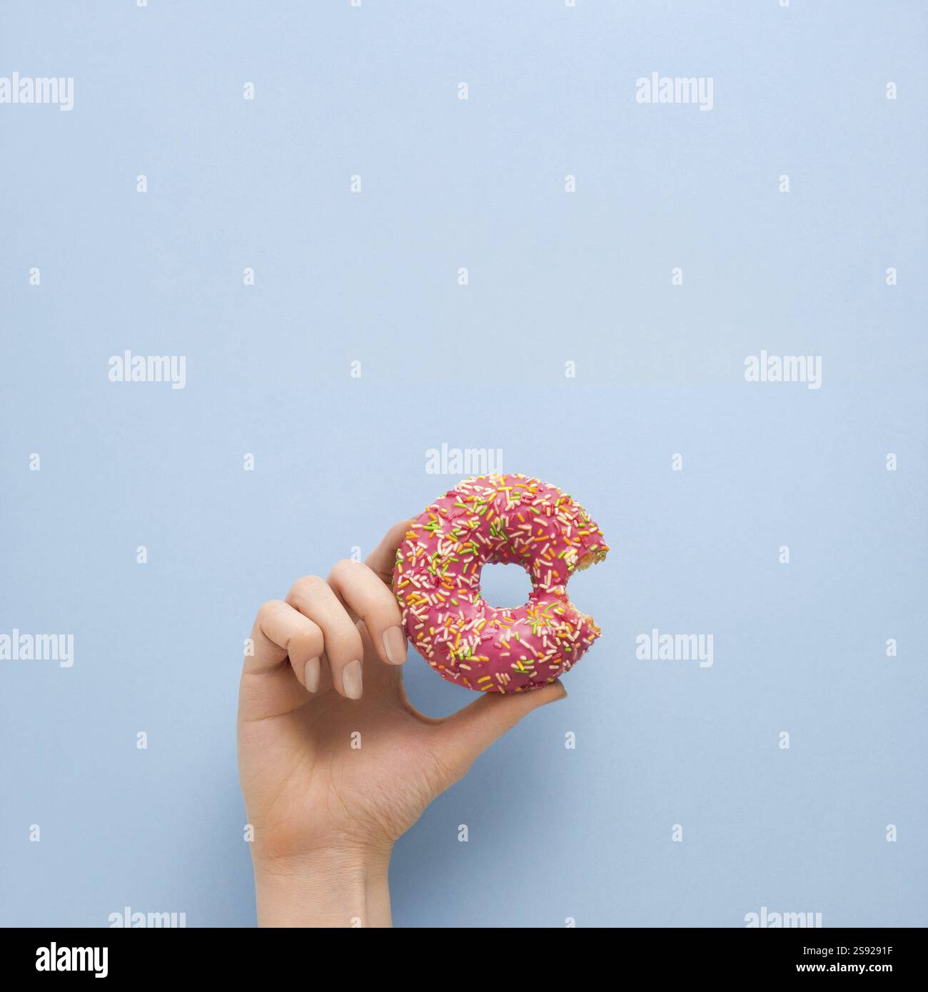 Foto creativa del concetto di ciambella tenuta a mano su sfondo blu Foto Stock