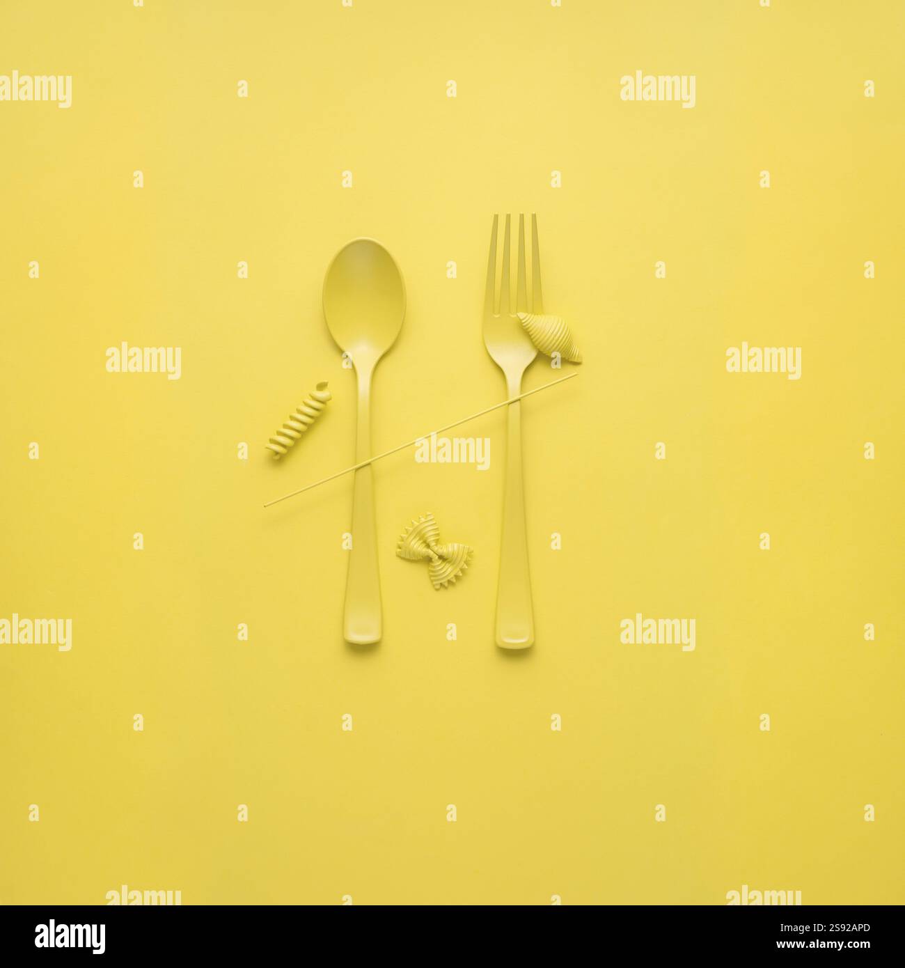 Foto creative di STILL Life con forchetta e cucchiaio con pasta cruda su sfondo giallo Foto Stock
